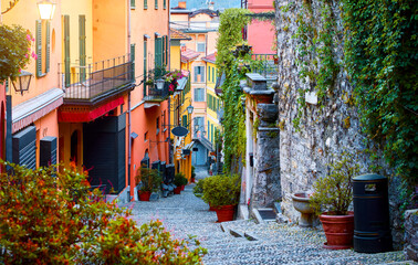 Naklejka premium Bellagio, lake Como, Milan, Italy. Famous stone stairs street. Evening Nighttime with blue sky and lights of outdoor lanterns. Picturesque italian architecture famous luxury Alpine health resort