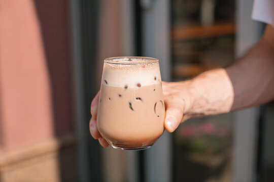 Close-up of a man's hand holding a mocha coffee