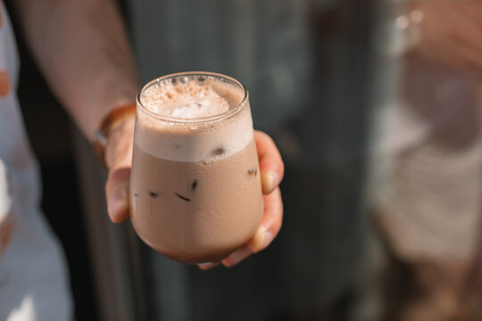 Close-up of a man's hand holding a mocha coffee