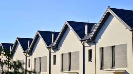 Suburban neighborhood with condominium complex. Suburban area with modern geometric family houses. Row of family houses against blue sky.