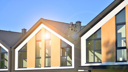 Suburban neighborhood with condominium complex. Suburban area with modern geometric family houses. Row of family houses against blue sky.