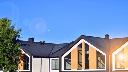 Suburban neighborhood with condominium complex. Suburban area with modern geometric family houses. Row of family houses against blue sky.