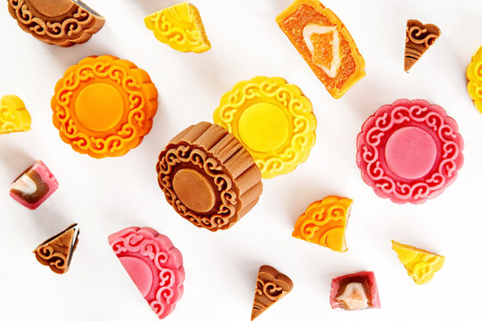 Overhead view of assorted multi coloured mooncakes on a white background