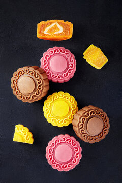 Overhead view of assorted multi coloured mooncakes on a black background