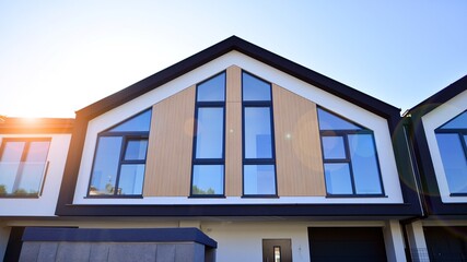 Suburban neighborhood with condominium complex. Suburban area with modern geometric family houses. Row of family houses against blue sky.