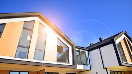 Suburban neighborhood with condominium complex. Suburban area with modern geometric family houses. Row of family houses against blue sky.