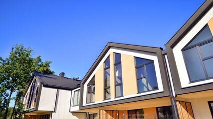 Suburban neighborhood with condominium complex. Suburban area with modern geometric family houses. Row of family houses against blue sky.