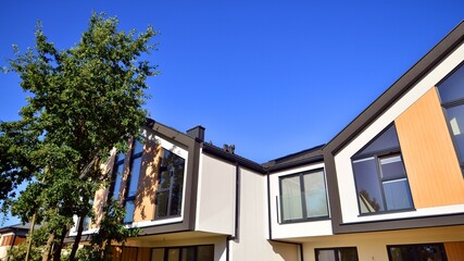Suburban neighborhood with condominium complex. Suburban area with modern geometric family houses. Row of family houses against blue sky.