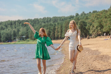 Smiling girls walking along coastline. Concept of friendship, entertainment and fun. High quality photo