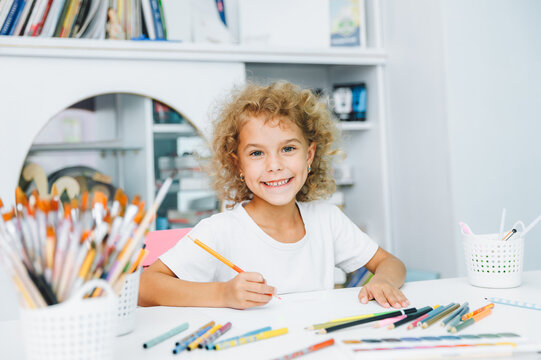 Cute little blonde preschooler girl draws at home