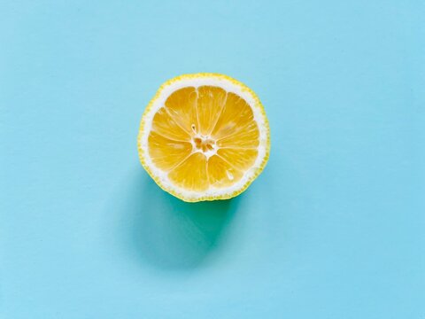 Overhead view of half a lemon on a turquoise background