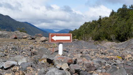 A wooden sign with an arrow points the way on a trail in a beautiful Chilean national park.