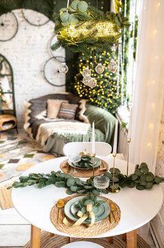 Decorated kitchen table in New Year's style. Many Christmas tree branches and fog trees