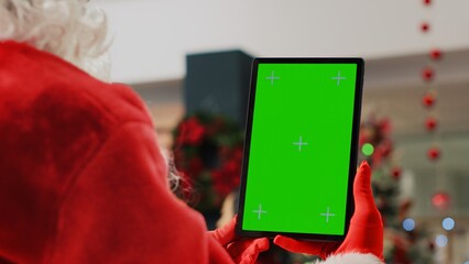 Xmas decorated shopping mall actor impersonating Santa Claus holding chroma key tablet, taking a...