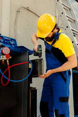 Worker using power tool to fix system electrical issues caused by broken evaporator coil. Repairman...