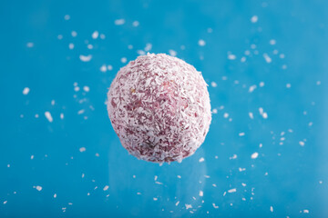 Boule proteinée énergisante coco avec écorce de citron sur fond coloré vif