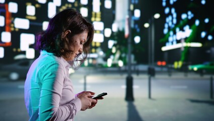 Adult on smartphone walking near city center, looking at maps for directions on night promenade....