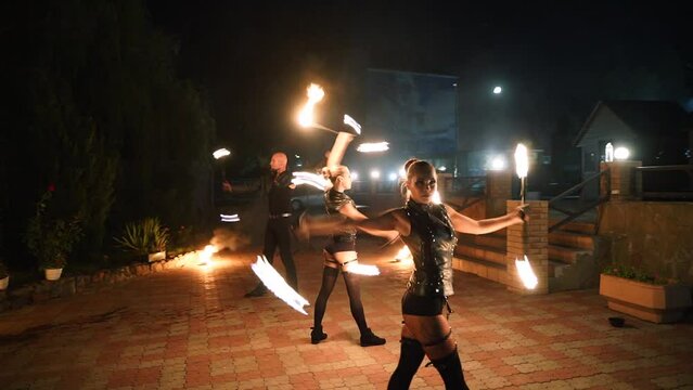 Fire performance show. Artists spin burning poles at night. Outdoor tribal dance with flames. Man and women dancers troupe act with torches at venue for tourists. Fire arts team juggling on festival.