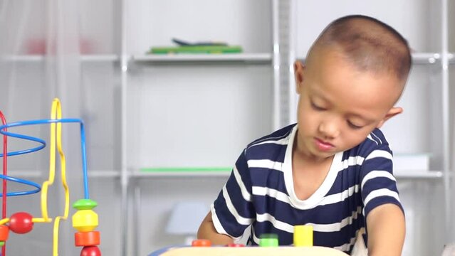 boy plays with developmental toys on the table inside the house