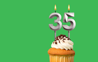 Birthday with number 35 candle and cupcake - Anniversary card on green color background