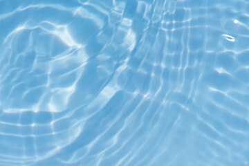 Defocus blurred transparent blue colored clear calm water surface texture with splashes reflection. Trendy abstract nature background. Water waves in sunlight with copy space. Blue watercolor shine.