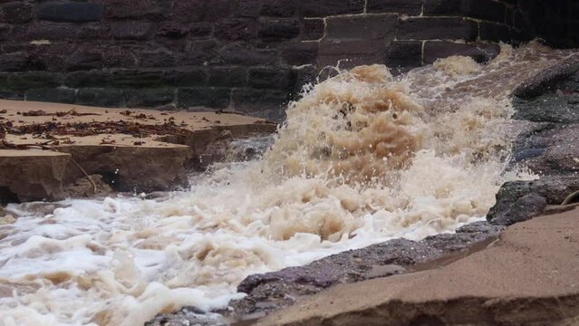 Rapid flood waters from heavy rain exiting broken sewer