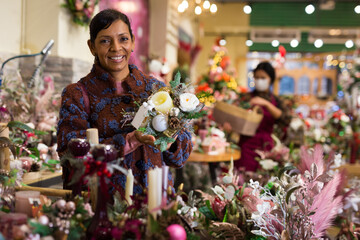 Happy american woman buying New Year decor at flower shop. Christmas decoration shopping
