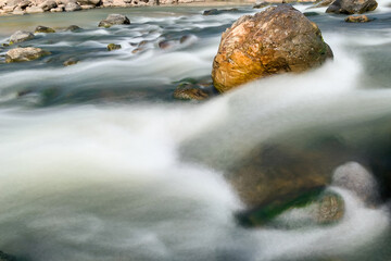 Stone in the midle of the river. River´s water flows around the stone.