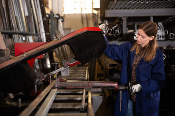 Female worker cuts metal profile pipe on a band saw. High quality photo