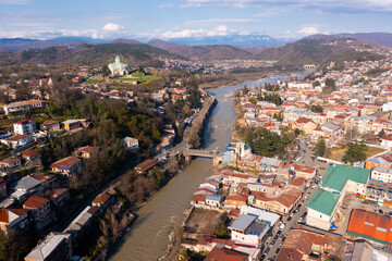 Fototapeta na wymiar View from drone of houses of georgian Kutaisi city on banks of Rioni river in spring day