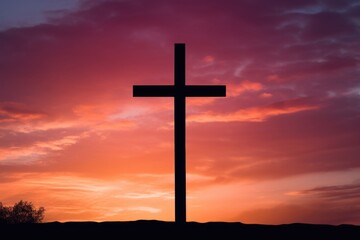 Concept photo of a cross silhouette, standing tall on the horizon as the sun sets behind it. The vibrant oranges and pinks of the sky reflect the warmth and comfort that faith can bring to