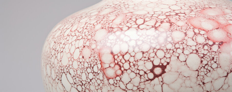 Closeup of Mottled Porcelain Pottery This delicate porcelain pottery showcases an intricate mottled pattern, with fine lines of glaze in shades of pink, gray, and ivory. The smooth and polished
