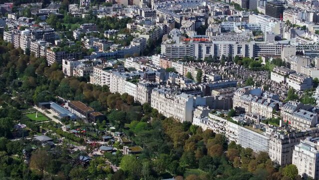 Fly above amusement park in Jardin d acclimatation. Buildings in surrounding urban neighborhood. Paris, France