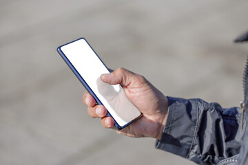 Detail of  the hand of a Latin man holding a mobile phone with a blank screen.