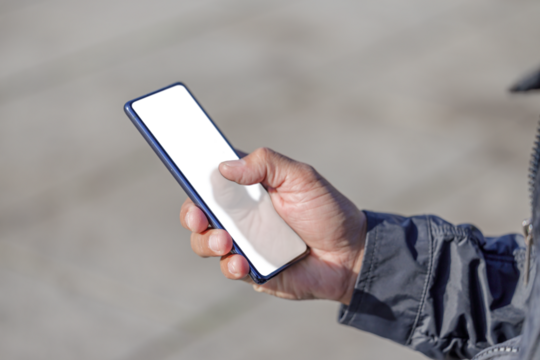 Detail of  the hand of a Latin man holding a mobile phone with a blank screen.