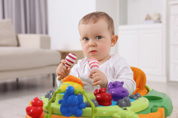 Portrait of cute baby with toy walker at home. Learning to walk
