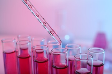 Dripping reagent into test tube with red liquid, closeup. Laboratory analysis