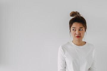 Asian Thai woman bun hair dislike sad face, sulking and frowning disappointed look at empty space,...