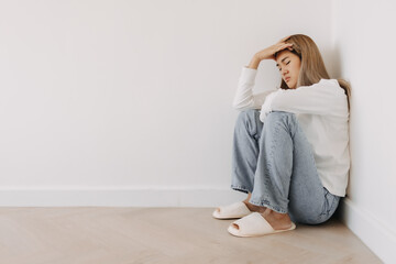 Asian Thai woman sitting on the heels, squatting, got headache with migraine, thinking too much, have no idea, tired in white apartment room in winter.