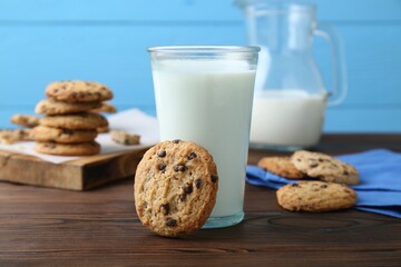 Delicious chocolate chip cookies and glass of milk on wooden table