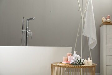 Stylish bathroom interior with ceramic tub and spa products on table
