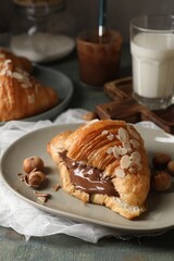 Delicious croissant with chocolate and nuts on table