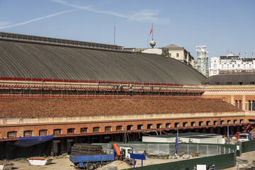 One of the facades of the Atocha station in Madrid that is undergoing renovation works with some workers repairing part of the cover