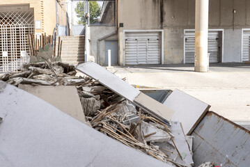 waste wood, plasterboard partitions and brick from a home renovation project deposited in a waste container on the street