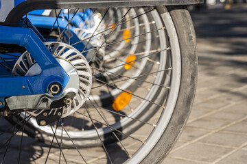 Fototapeta premium A pile of bicycle wheels parked at an electric charging station on a central street in a European city