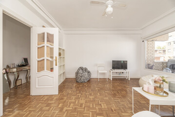 Large living room of an apartment with a few white furniture, white lacquered glass access doors and slatted oak parquet floors - obrazy, fototapety, plakaty