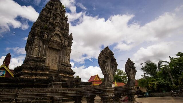 Angkorian like temple structure with protective naga snake at the entrance. Place of worship with fluffy monsoon clouds building on blue sky. Pagoda, Siem Reap, Cambodia, motion control time lapse.