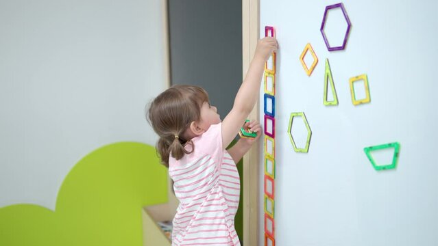 Toddler Girl Playing With Magnetic Square Tiles. 3-Year-Old Kid Building Row from Magnet Blocks on Chalkboard. Creativity Educational Toys for Kids