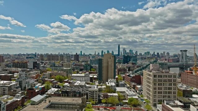 Aerial forward flight over noble district in New York City with Williamsburg Bridge during sunny day -Beautiful cityscape with skyline in backdrop