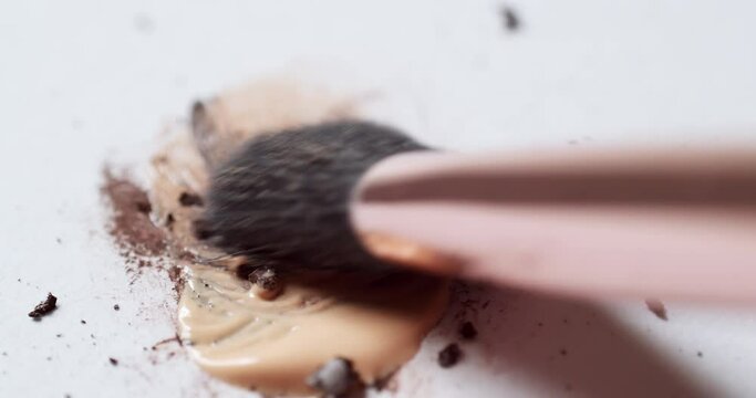 Blending a dark-brown toned mascara loose powder using an eyelash wand applicator on a blank white board.